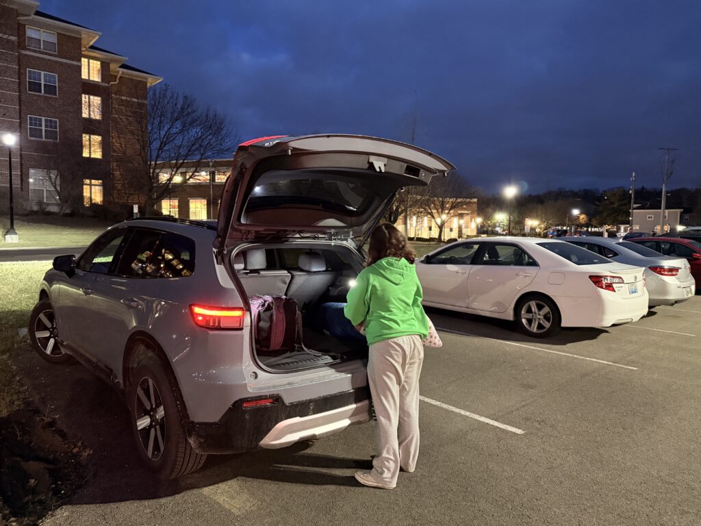 A young female in green sweatshirt accessing the trunk of a Honda Prologue EV at night